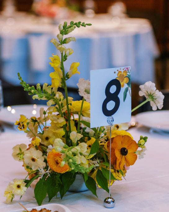 Table setting with floral centerpiece and table number 8 in a formal dining room.