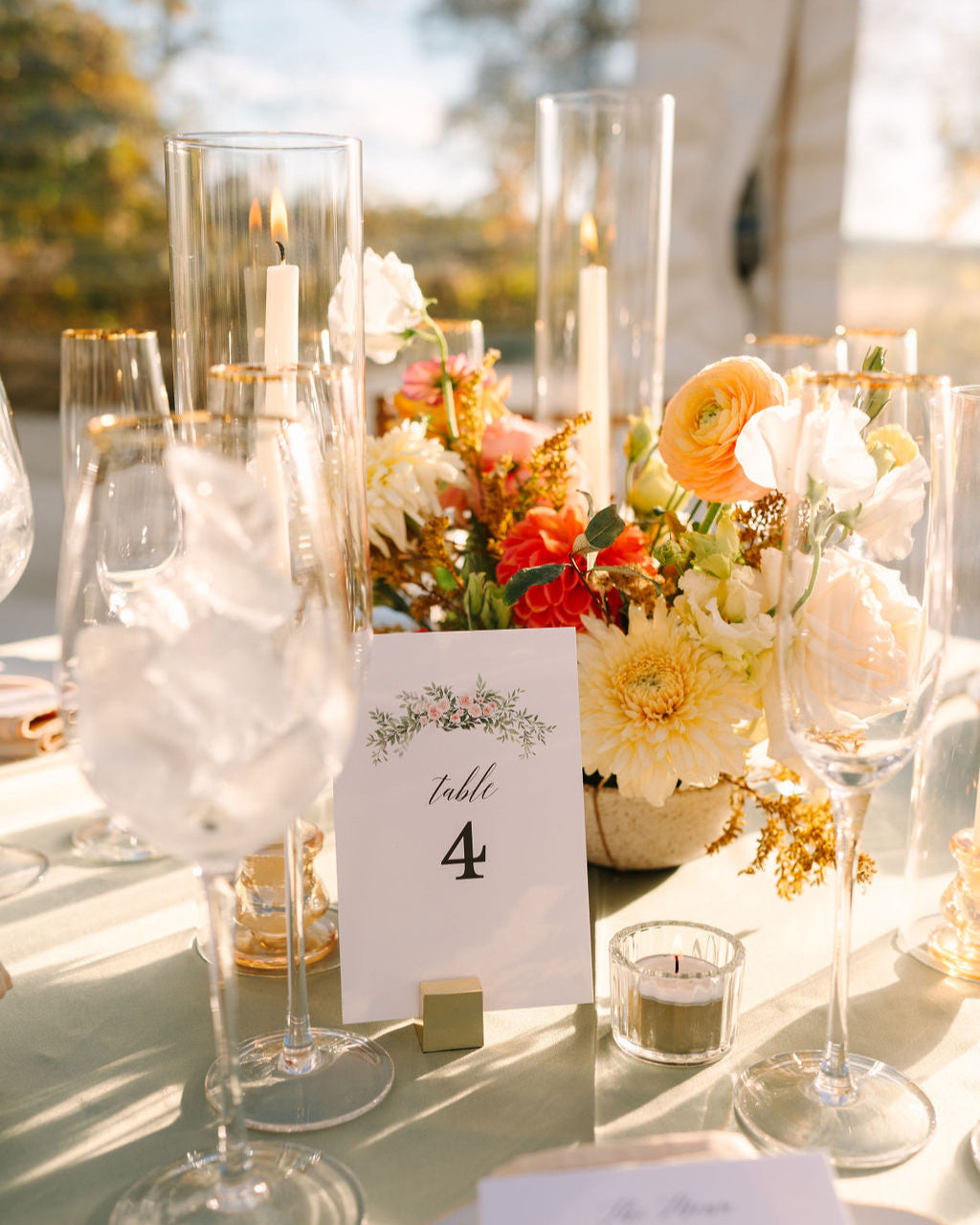 Elegant outdoor wedding table setting with flowers, candles, and a table number.