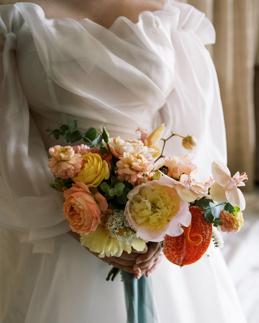 Bouquet of flowers held by a person wearing a white dress.