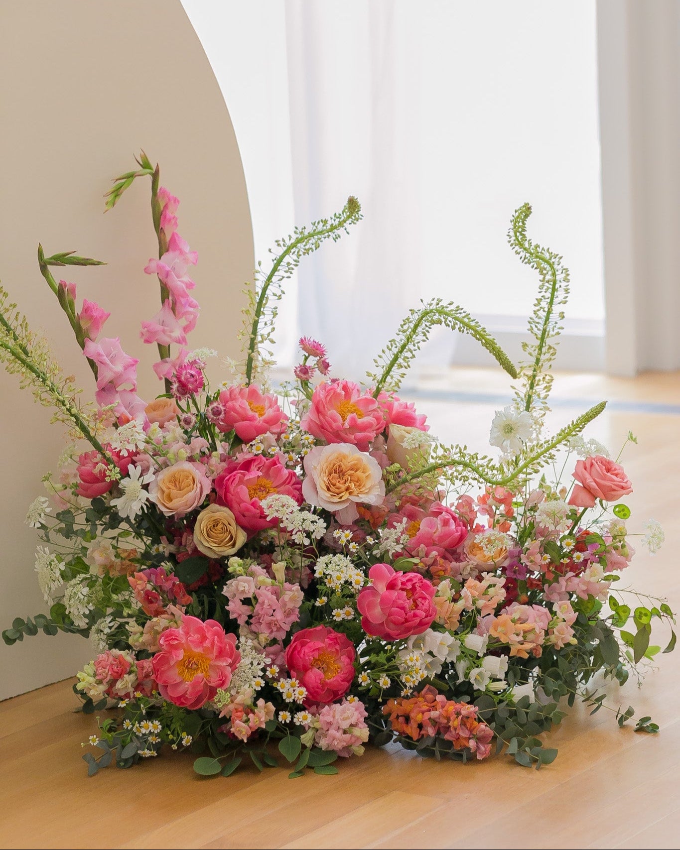 Bouquet of flowers on a wooden floor with a white curtain in the background
