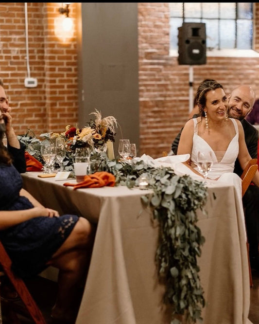 Wedding reception with guests seated at tables in a brick-walled room.
