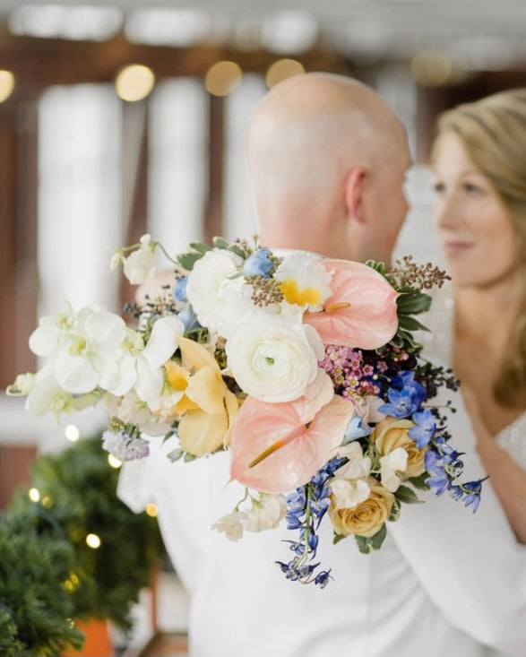 Bride and groom holding a colorful bouquet with a blurred background