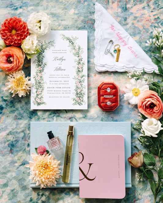 Wedding invitation set with flowers and jewelry on a textured surface