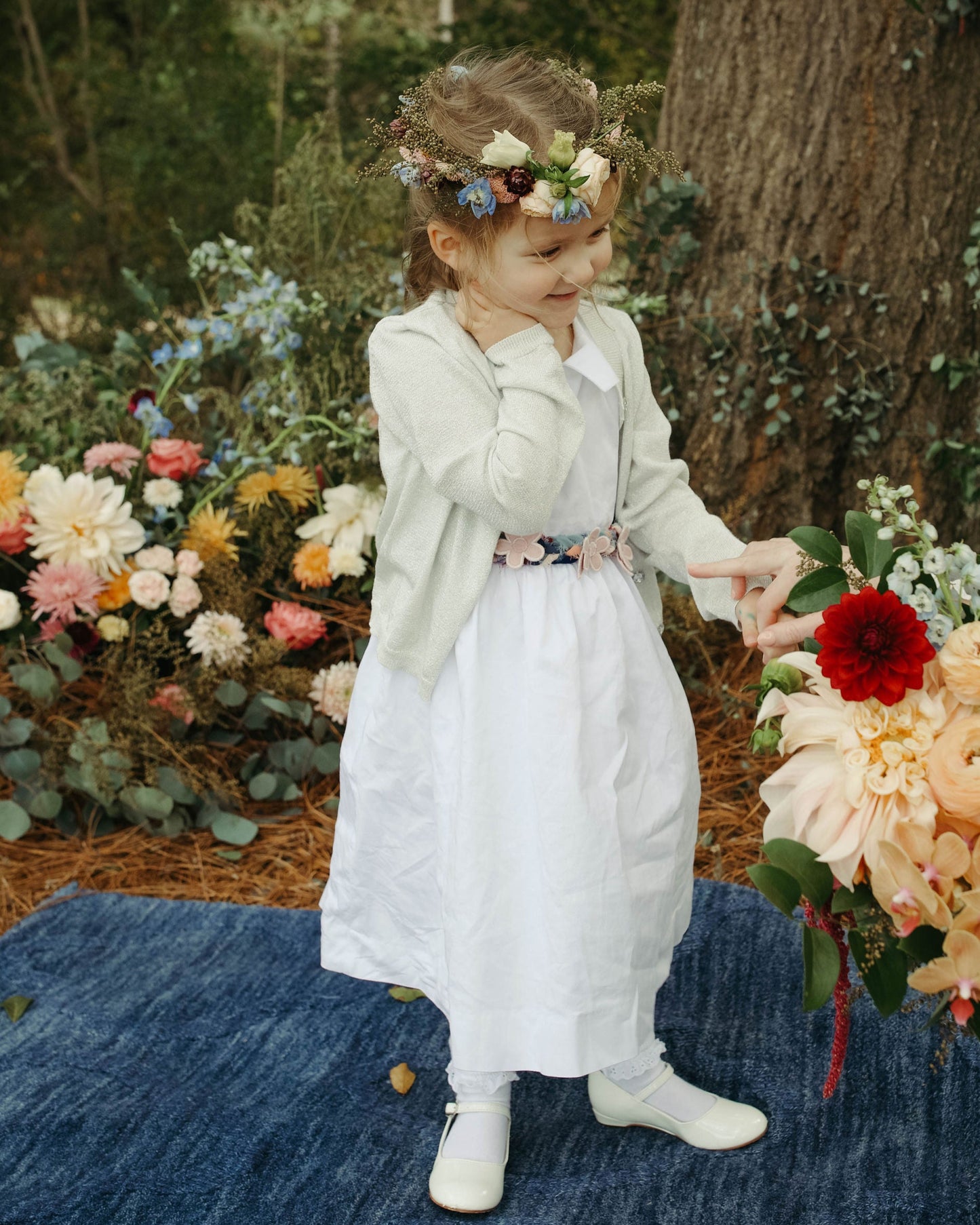 Two children in formal attire standing in a garden with floral decorations.